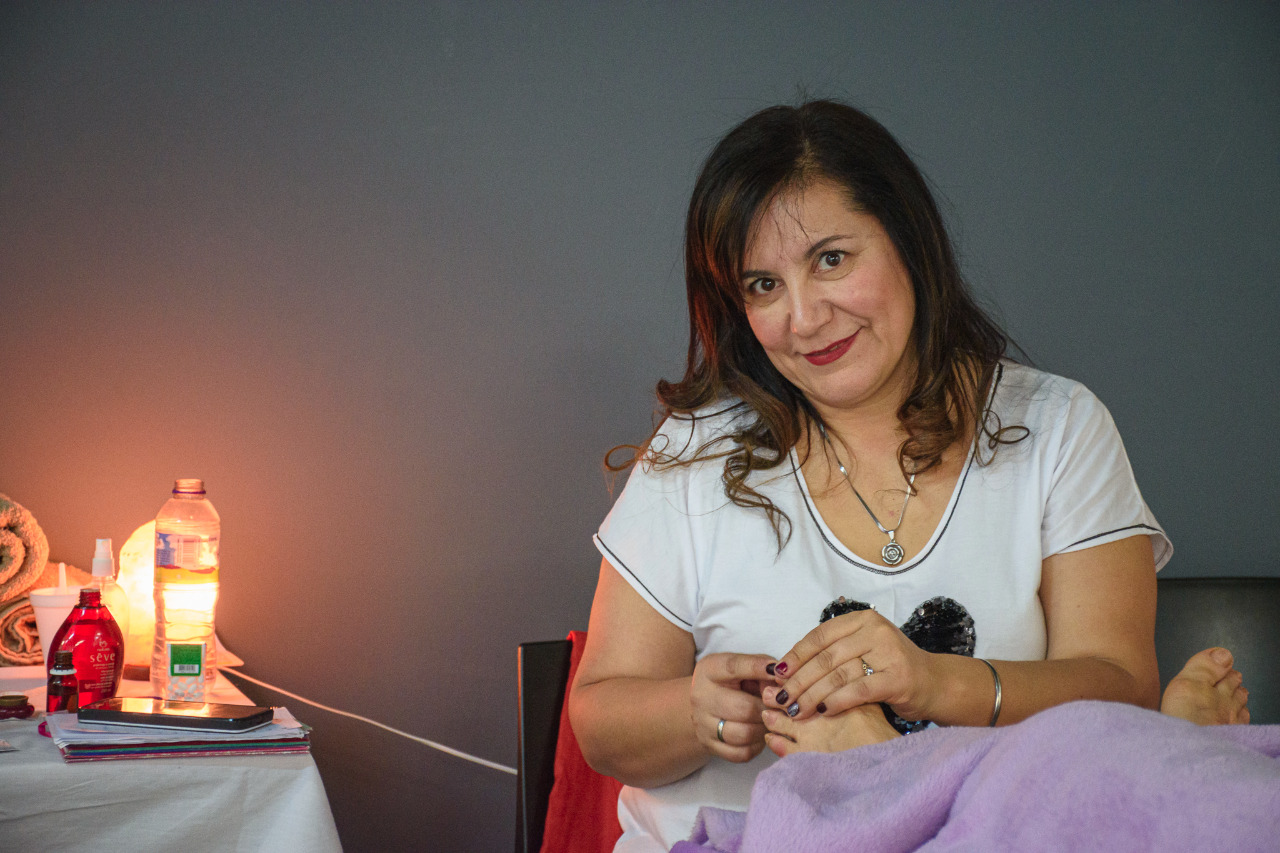 Rut Carolina Durante atendiendo con dedicación a clienta en sesión de reflexología podal en consultorio acogedor